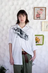 Camisa blanca de algodón con cuello clásico, manga larga con puños abotonados y estampado frontal de un animal similar a un zorro.