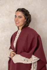 Ruana abierta de color beige, confeccionada en tejido de punto con terminación de flecos en el ruedo.