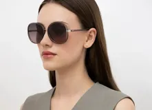 Lentes de sol INVU con montura redonda plateada y lentes degradadas de gris a rosa.