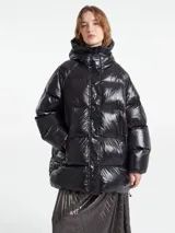 Campera puffer de corte holgado con acabado brillante, cierre frontal y capucha integrada.