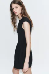 Vestido corto negro confeccionado en 100% algodón, de cuello redondo y mangas cortas. Presenta detalle de lazadas en los laterales de la cintura y falda con vuelo.