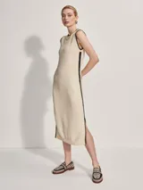 Vestido midi tejido color crema con ribete negro en cuello, sisas y ruedo. Presenta aberturas laterales en el ruedo.