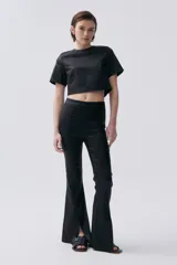 Pantalón negro de corte ajustado con aberturas en el ruedo.