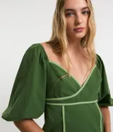 Vestido corto de tricolina color verde oscuro con detalles de bies en tono verde claro contrastante, escote cruzado en V, mangas cortas abullonadas y cierre en la espalda.