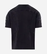 Remera boxy de algodón color negro con efecto desteñido, cuello redondo, mangas cortas y hombreras estructuradas con recortes y pespuntes.