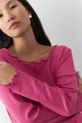 Remera blanca de manga larga con cuello redondo y costuras a la vista.