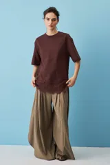Remera blanca de algodón, de corte oversize, manga corta y cuello redondo, con detalle de aplique de encaje floral en el borde inferior.