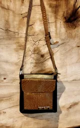 Bandolera Orlena de la línea Ottenta, confeccionada artesanalmente con cueros uruguayos seleccionados con distintas texturas. Presenta un diseño combinado en negro, marrón con textura símil cocodrilo y detalles en tono dorado, con correa ajustable para usar al hombro o cruzada y herrajes de metal.