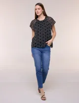 Blusa holgada de gasa negra con estampado geométrico de círculos blancos, cuello redondo fruncido con volados y mangas cortas de corte mariposa.