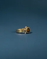 Anillo de plata 925 con baño de oro 24k, de banda chata y piedra citrino facetada central enmarcada por pequeñas esferas.