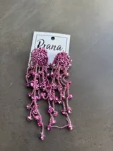 Aros colgantes con base circular cubierta de cuentas rosas y flecos de cuentas y flores rosas.