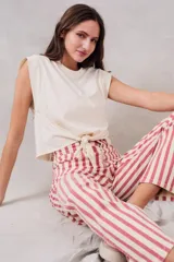 Top de algodón peinado color crudo, con cuello redondo, hombreras marcadas y detalle de nudo frontal ajustable.