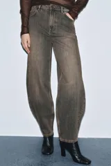 Jeans de tiro medio con diseño de pierna curva tipo barrel, confeccionados en denim con efecto lavado. Presentan cintura con trabillas, cierre frontal con cremallera y botón, y cinco bolsillos clásicos.