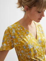Vestido midi cruzado de color ocre con diseño floral estampado, escote en V y mangas cortas con vuelo. Cuenta con un lazo ajustable en la cintura.