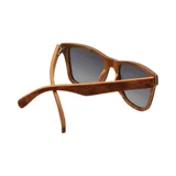 Lentes de sol con montura de madera color marrón claro y lentes grises degradadas. Patillas de madera con el logo de la marca Indie.