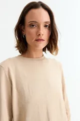 Sweater de punto liso color marrón topo, con cuello redondo y manga larga. Presenta un detalle de tres botones pequeños en la abertura del puño.