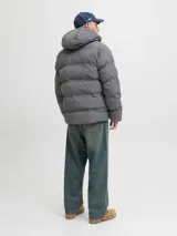 Campera puffer de color gris oscuro, con capucha integrada, cierre frontal completo y diseño acolchado horizontal. Cuenta con bolsillos laterales y acabado resistente al agua.