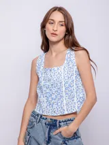 Top celeste con estampado de flores blancas, corte crop, breteles anchos y botones frontales.