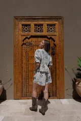 Short de tiro medio con pierna holgada, color blanco con estampado de motivos florales en tonos tierra. Presenta bolsillos delanteros y un cordón de ajuste en la cintura.