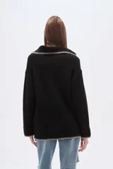 Sweater negro holgado con cuello en V y ribete en color crema en cuello, puños y ruedo.