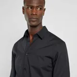 Camisa negra de corte recto, manga larga y cuello clásico.