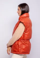 Campera puffer de diseño ochentoso con mangas removibles que permiten convertirla en chaleco. Presenta cuello alto, cierre frontal y cordón ajustable en la cintura.