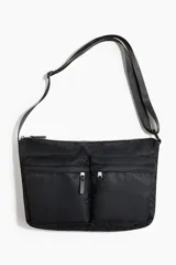 Cartera cruzada acolchada de color negro con dos bolsillos frontales con cierre, correa ajustable y cierre superior.