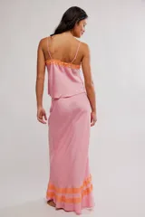 Conjunto de dos piezas de satén rosado, compuesto por una musculosa con tirantes finos y detalles de encaje naranja en el escote, y una falda larga al bies con volados y encaje naranja en el ruedo.