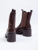 Bota tipo Chelsea de caña alta, confeccionada en cuero sintético negro, con paneles elásticos laterales y suela track con plataforma.