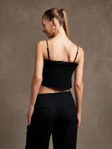 Top corto negro con breteles finos y detalle de volados en el escote.