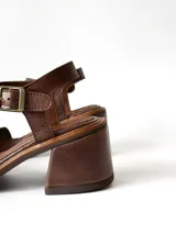 Sandalias de cuero color chocolate, con taco cuadrado de 6 cm, tira ancha en la parte delantera y tira en el tobillo con hebilla metálica ajustable.