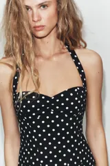Top negro con estampado de lunares blancos, escote halter y diseño estructurado tipo corset con copas fruncidas en el centro.