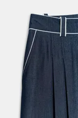 Bermuda ancha de tiro alto, confeccionada en denim color azul, con pinzas delanteras y detalles de vivos a contraste. Cuenta con cierre frontal con cremallera y botón.