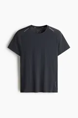 Remera deportiva para running de color gris oscuro, confeccionada en tejido técnico con tecnología DryMove. Presenta cuello redondo, mangas cortas, detalles reflectantes en los hombros y aberturas laterales en el bajo.
