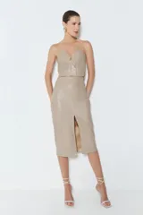 Falda midi color beige de cuero sintético, tiro alto y corte recto con abertura frontal.