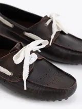 Mocasín de cuero vacuno con efecto gastado, diseño de la colaboración Jazmín Chebar x Guido. Presenta detalles de picado en laterales y capellada, con cordones blancos y suela de goma con relieve.