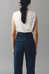 Jean de tiro alto con corte mom slim, confeccionado en denim azul oscuro con leve elasticidad. Presenta diseño de cinco bolsillos, cierre con botón y pierna recta que se estrecha ligeramente hacia el bajo.