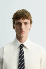 Corbata ancha de seda, color azul marino, con diseño de rayas diagonales en tonos beige y rojo.