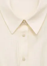 Camisa blanca sin mangas con pinzas en la cintura, cuello camisero y cierre frontal con botones.