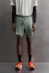Short de entrenamiento deportivo con diseño 2 en 1, que incluye una capa exterior de tejido técnico ligero y una malla interior ajustada. Cuenta con cintura elástica con cordón de ajuste, bolsillos laterales con cierre y aberturas en el bajo.