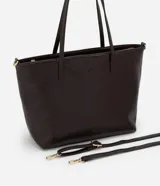 Cartera tipo shopper de gran tamaño, confeccionada en poliuretano con textura efecto crocco. Presenta doble asa fija para llevar al hombro y una correa larga desmontable con herrajes dorados. Cuenta con cierre superior por cremallera.