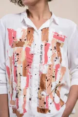 Camisa blanca de viscosa con arte abstracto pintado a mano por Carolina De Cunto en tonos rosa, blanco y cobre, de manga larga y cierre frontal con botones.