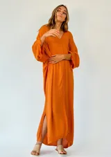 Vestido largo color amarillo mostaza, de corte amplio y mangas largas.