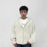 Campera de jean color hueso con capucha, cierre frontal con cremallera dorada, bolsillos laterales y puños elásticos.
