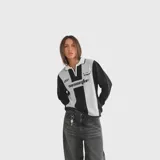 Sweater de punto con cuello polo y cierre frontal parcial, diseño bicolor en negro y gris con estampado gráfico frontal de estilo deportivo, mangas largas y puños acanalados.