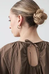 Top negro de manga corta con escote redondo y frunces en la costura de la sisa, creando un efecto de manga abullonada. El tejido parece ligero y con textura.