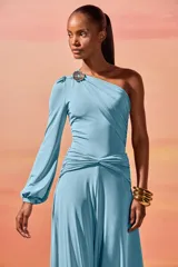 Body de un solo hombro confeccionado en jersey elástico. Presenta un diseño drapeado con una hebilla decorativa dorada en el hombro, manga larga con puño y detalle de fruncido en la cintura.