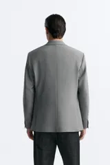 Blazer azul marino de corte recto, confeccionada en tejido con viscosa. Tiene cuello con solapas de muesca, manga larga con puño abotonado, bolsillo de vivo en el pecho y bolsillos de parche en la cadera. El bajo tiene aberturas en la espalda y el cierre es con botonadura frontal.