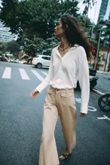 Camisa de cuello solapa y escote en pico, color marrón oscuro, de manga larga con puños anchos y cierre frontal con botones.