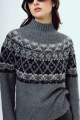 Sweater de punto color marrón, con cuello alto y diseño tejido con patrones geométricos en tonos negros y blancos en la parte superior y mangas.